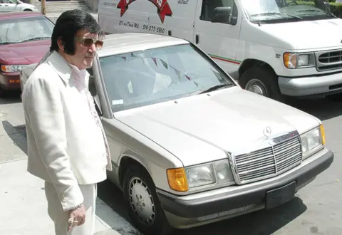 Elvis l'italiano - dir. André-Line Beauparlant, an Elvis impersonator stands next to a silver car